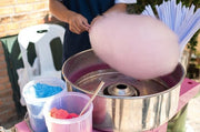 Person serving pink vanilla candy floss from cotton candy machine rental